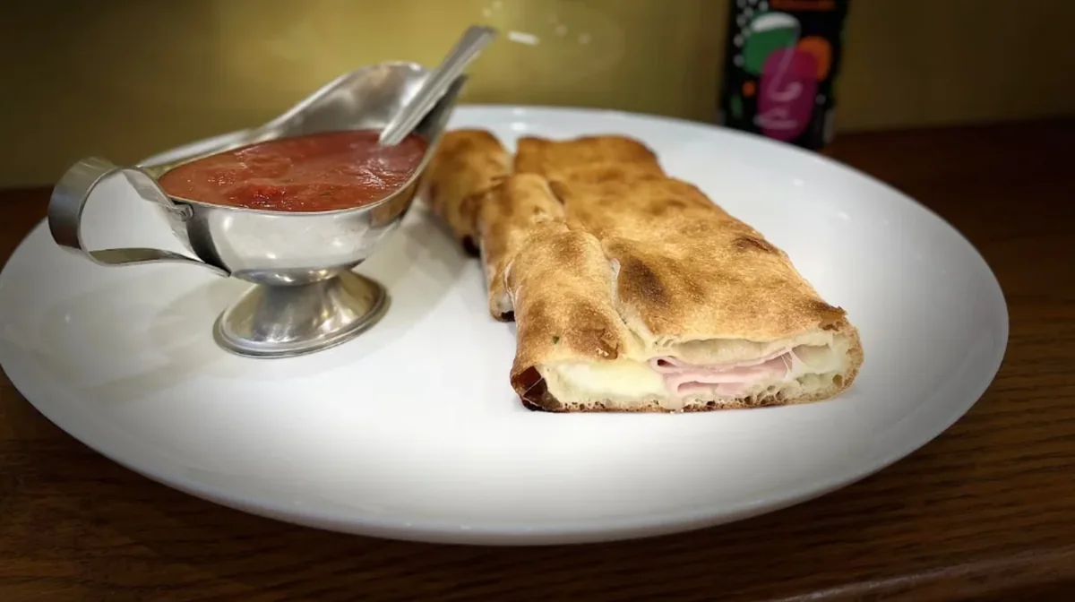 Pizza ripiena Gondola servită cu sos de roșii